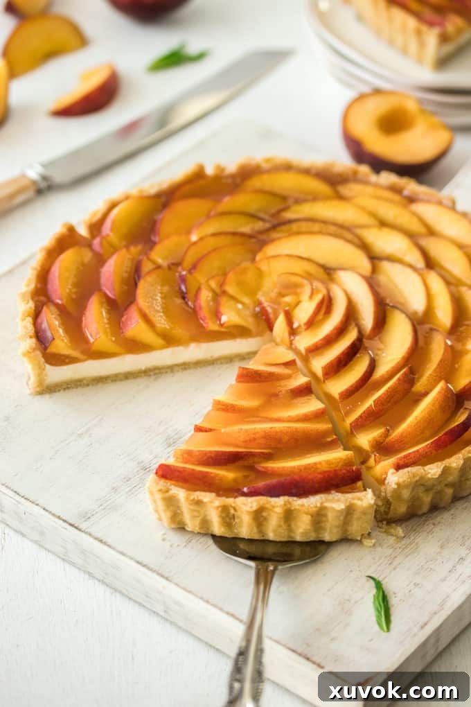 A Panna Cotta Fresh Peach Tart on a white board, a slice is missing, another slice on a cake server