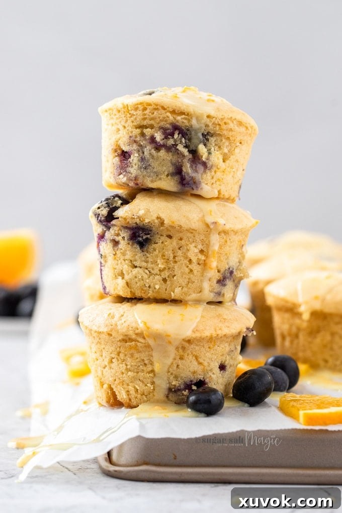 Three perfectly baked blueberry orange muffins stacked on parchment paper, ready to be enjoyed