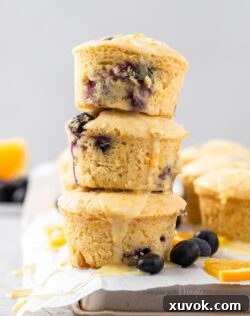 Three stacked blueberry orange muffins on parchment paper, representing the final baked product