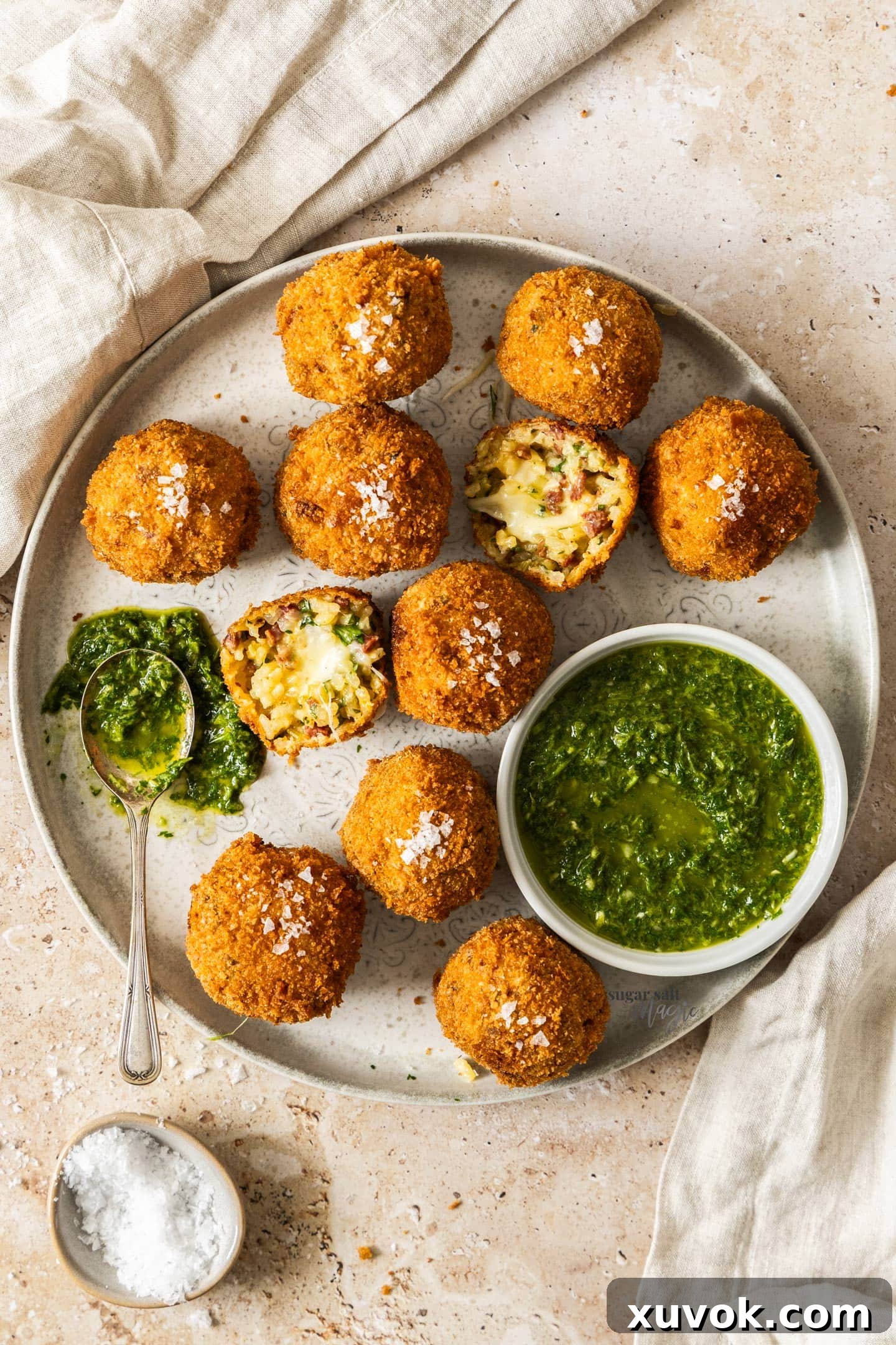 Top down view of a plate full of chorizo arancini with a bowl of mojo verde to the side.