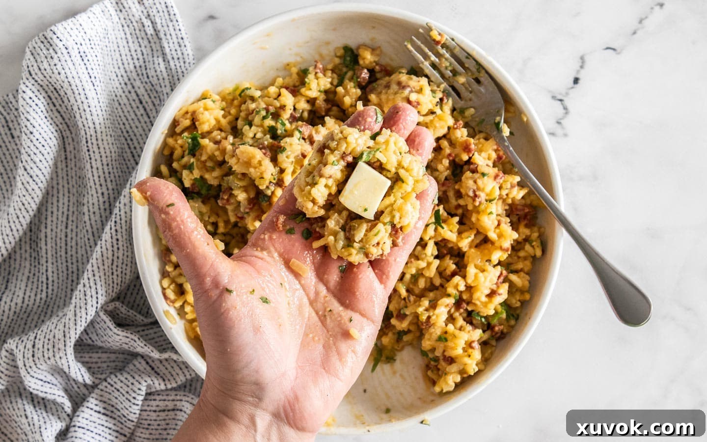 Hand holding a flat risotto disc with a mozzarella cube.