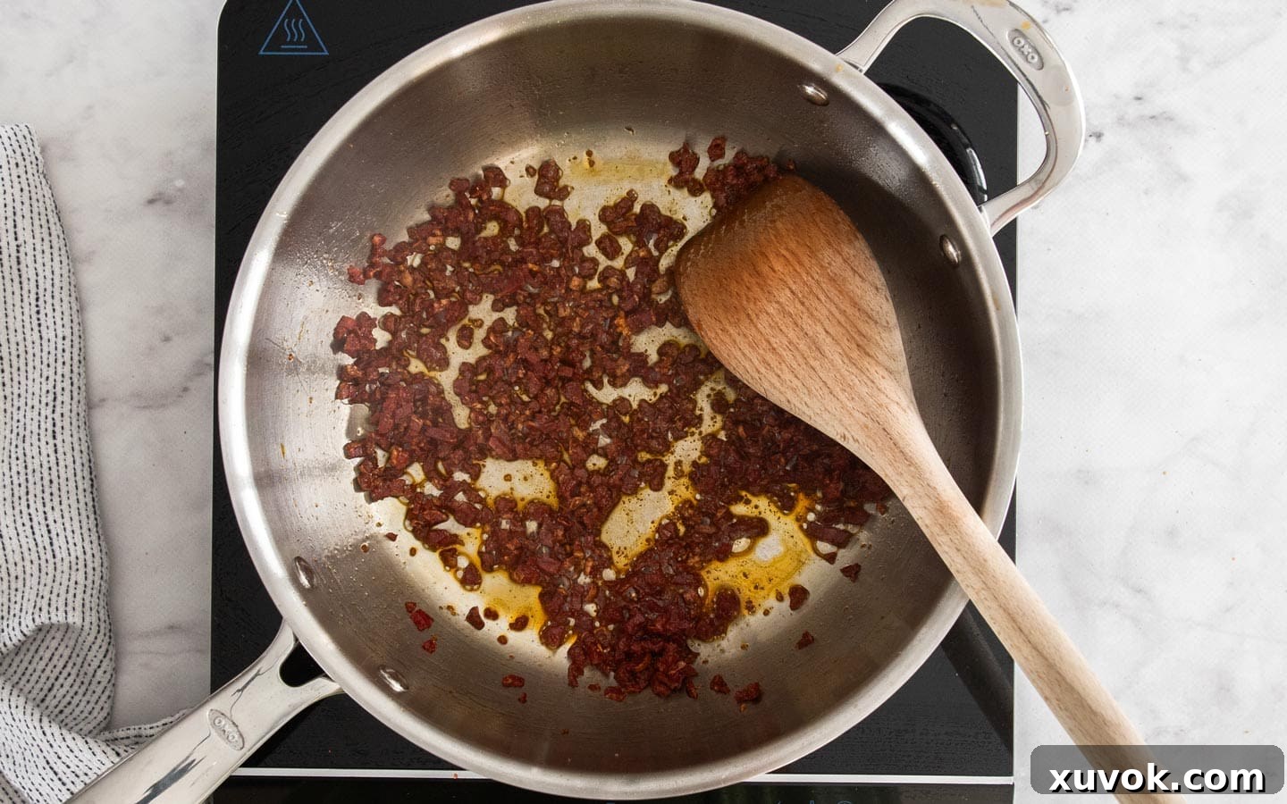 Diced chorizo cooking in a pan, releasing its oils.