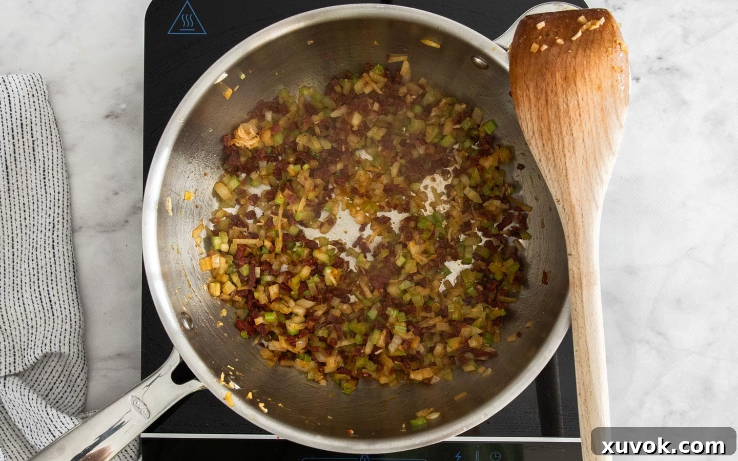 Onion, celery, and garlic cooking with chorizo in a pan.