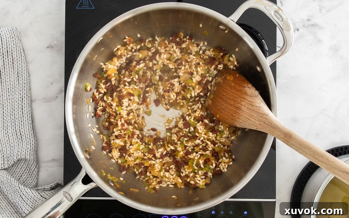 The rice absorbing the first ladle of stock in the pan.