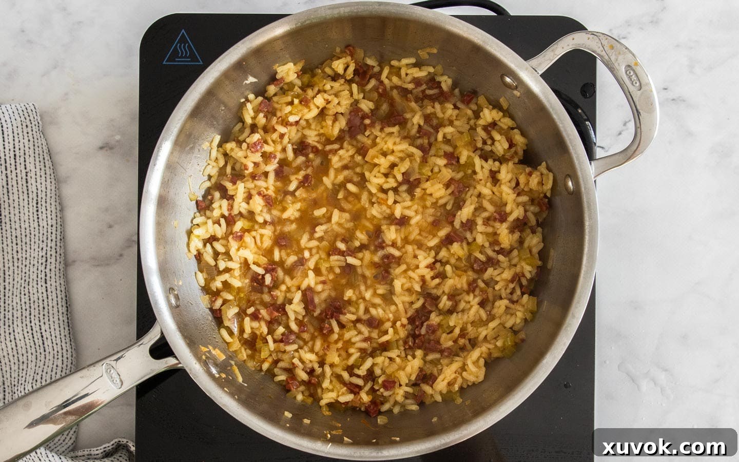 Cooked rice with a minimal amount of liquid remaining, ready for cheese.
