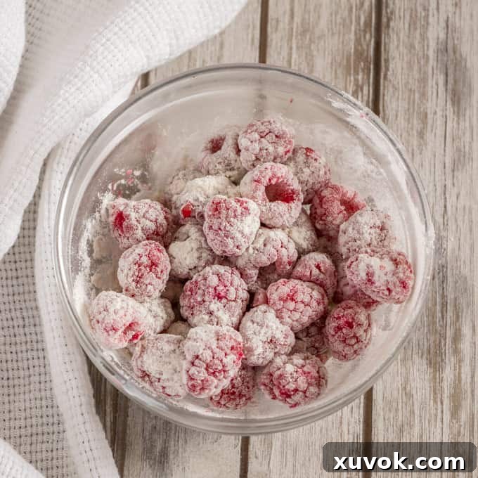 A bowl of raspberries coated in flour, ready to add to the cake batter.