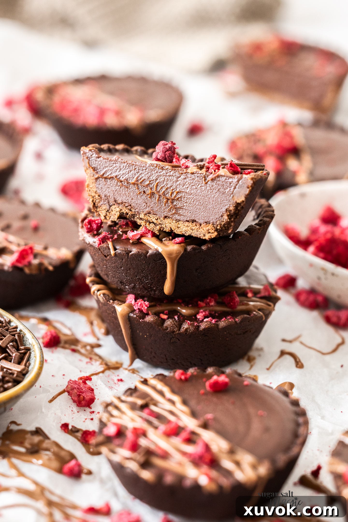 A stack of chocolate tarts wtih the top one cut in half.