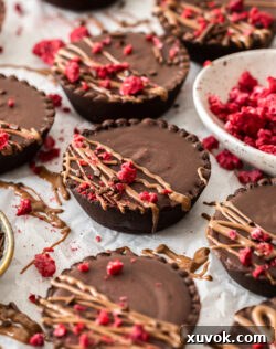 Closeup of a chocolate tartlet drizzled with chocolate and raspberries.