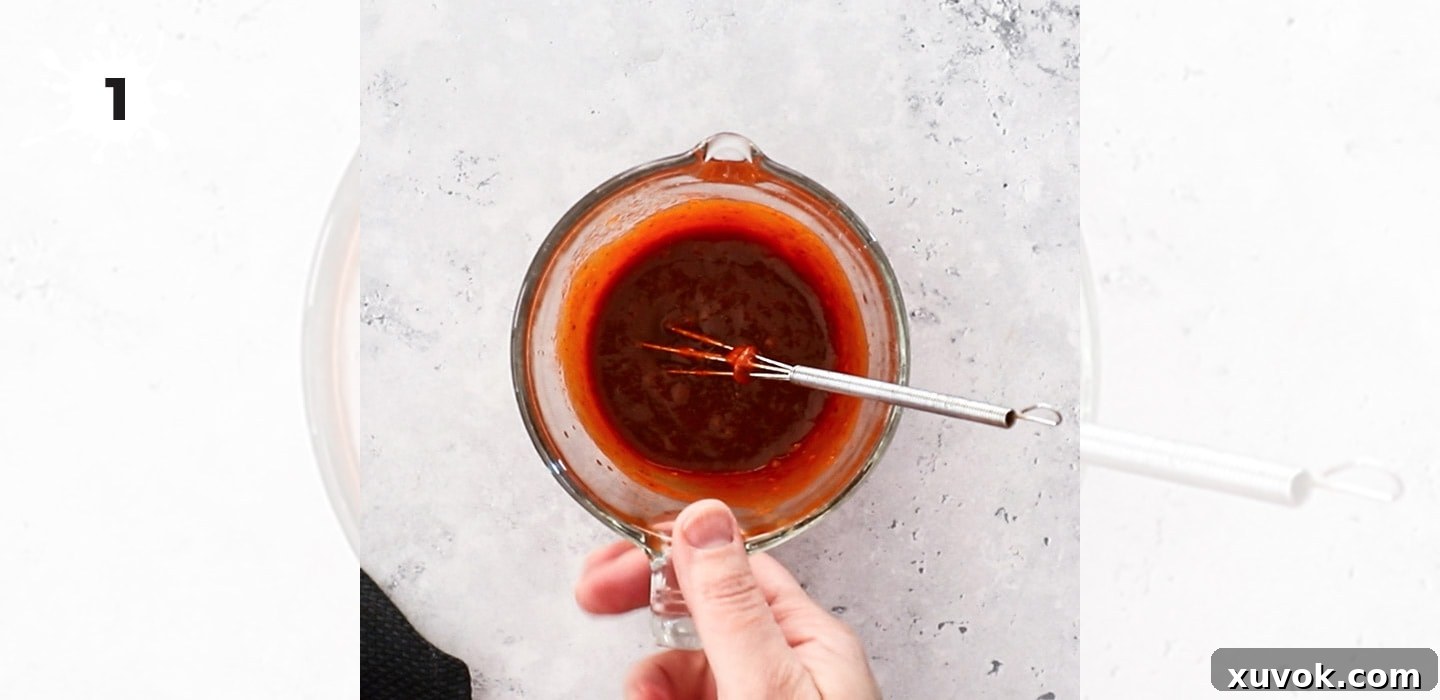 A small glass jug filled with the vibrant red harissa marinade, ready to be applied to the chicken.