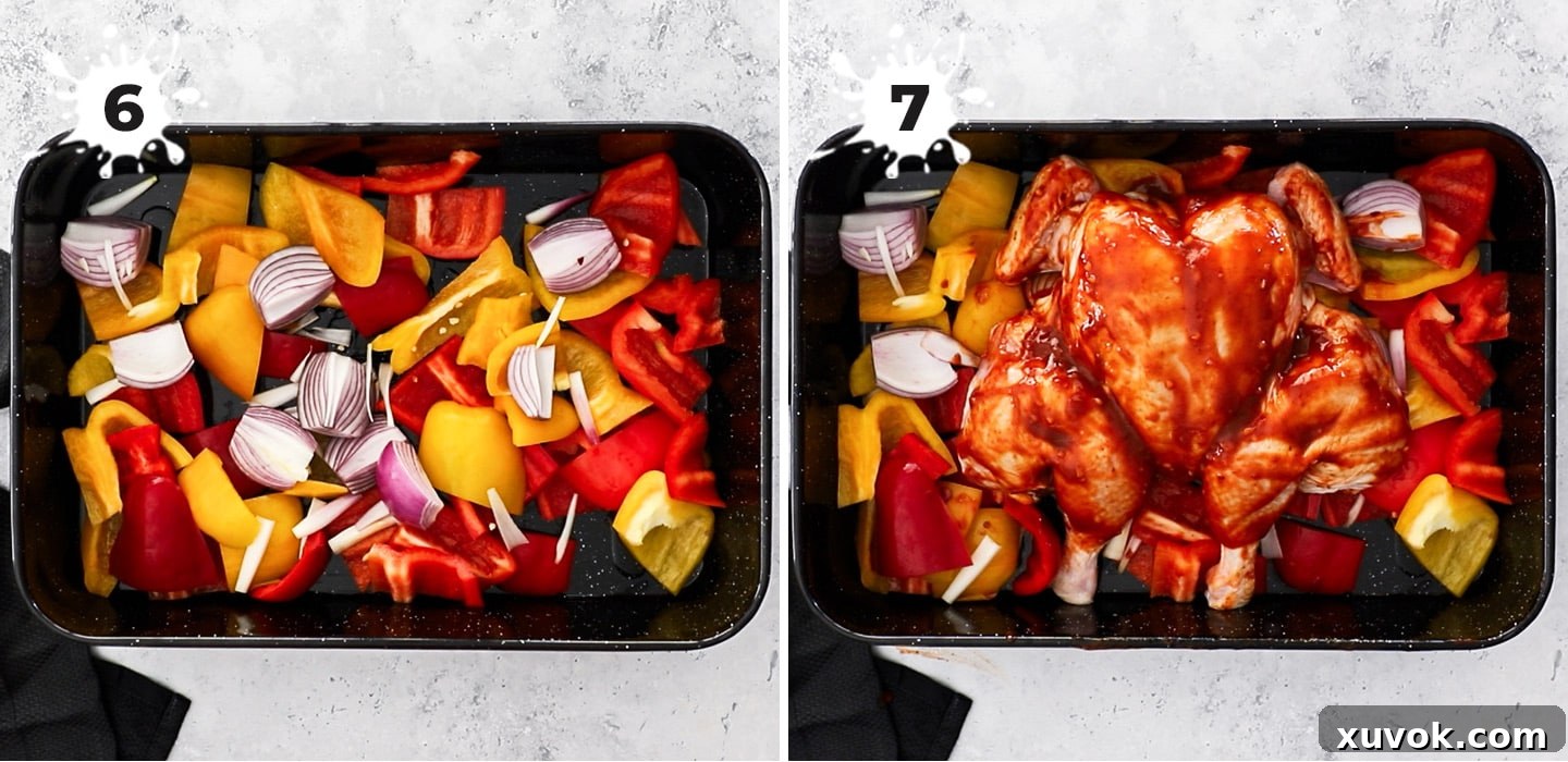 A roasting pan filled with chopped bell peppers and onions, with a butterflied whole chicken placed on top.