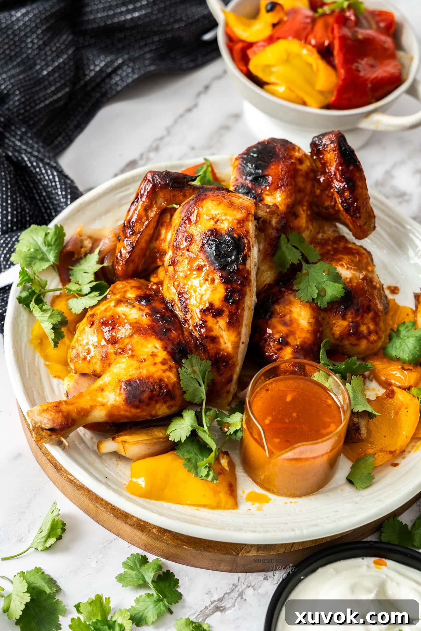 A whole roasted harissa chicken, butterflied and cut in two halves on a serving plate.