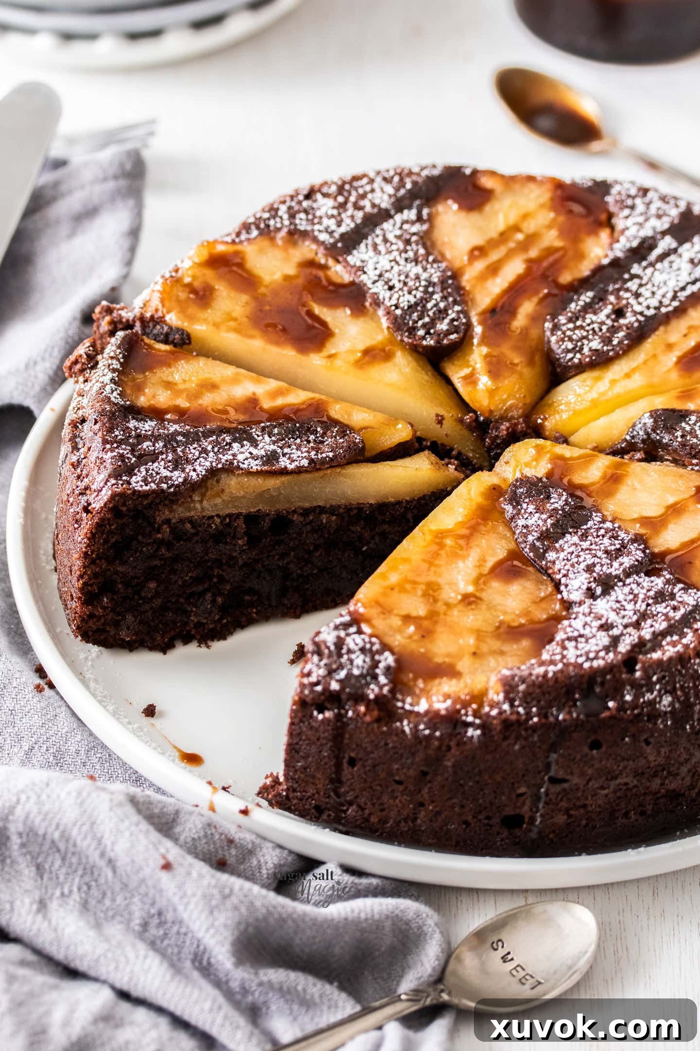 A chocolate pear cake, with one slice cut, showcasing the rich texture and fruit topping.
