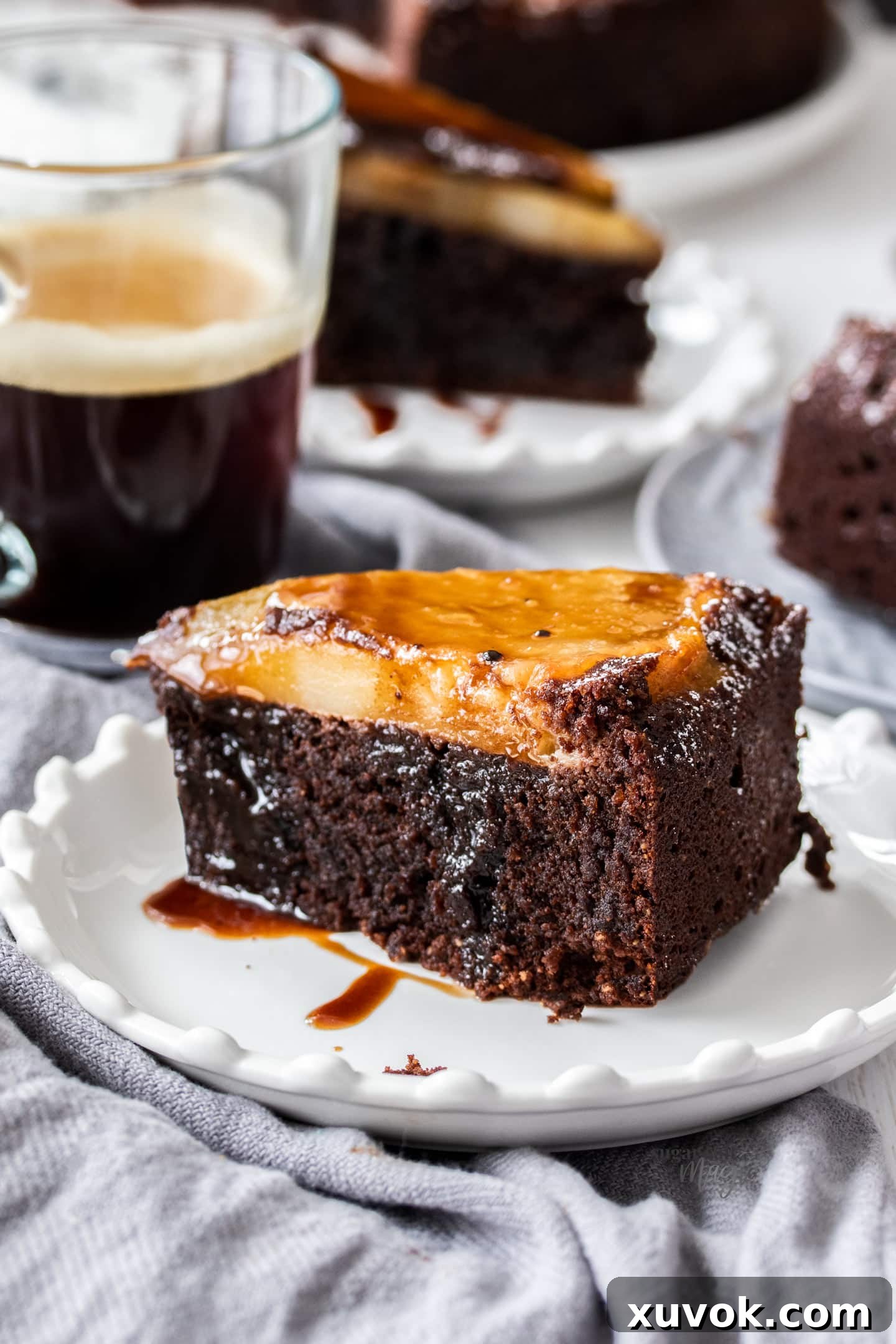 A slice of chocolate pear cake on a dessert plate, drizzled with syrup.