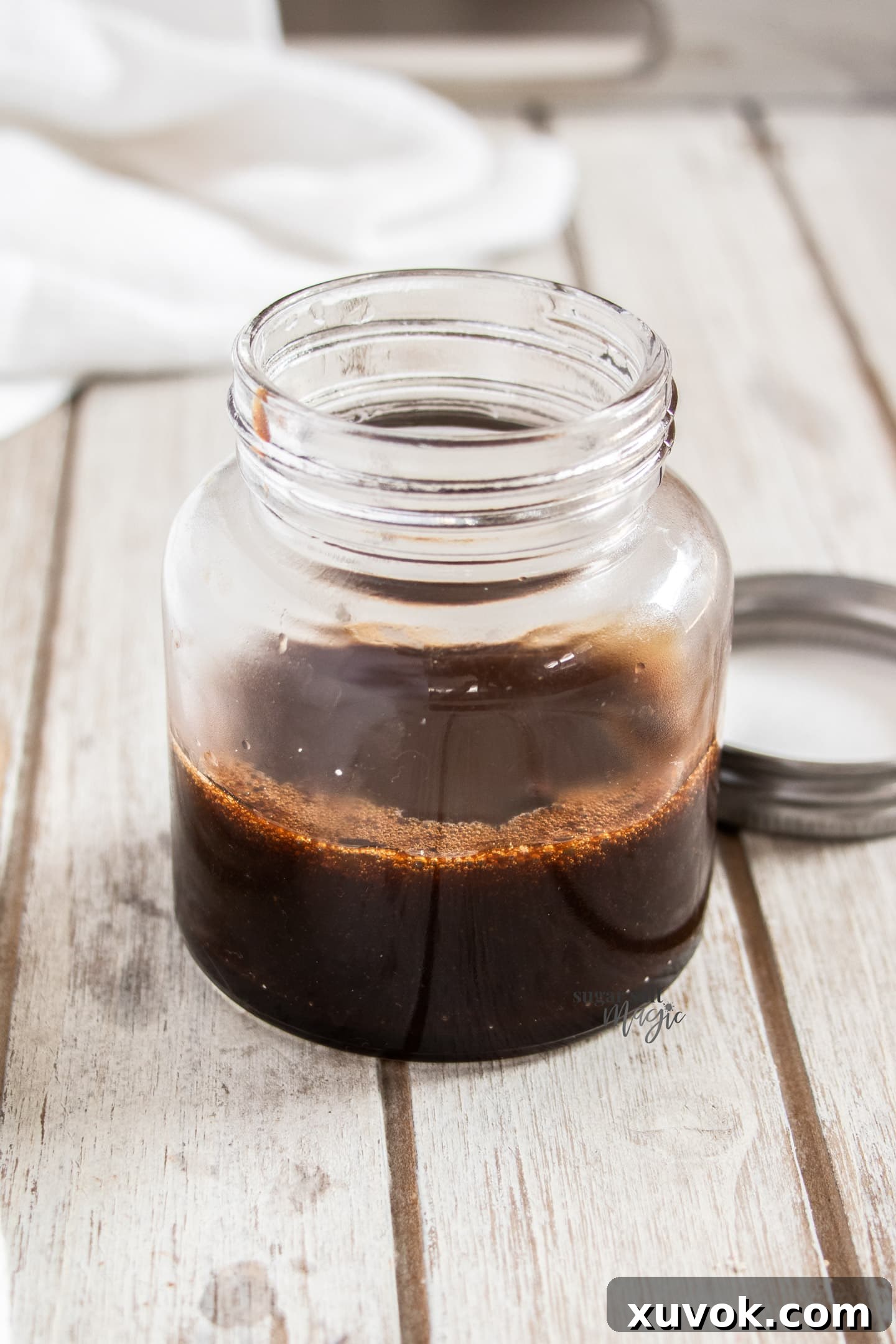 A jar half filled with the rich, thick pear poaching syrup.