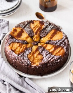 A chocolate cake topped with pears on a cake plate, sliced and ready to serve.
