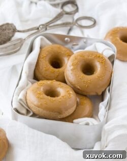 Cake donuts in a tin with dessert tongs next to them.