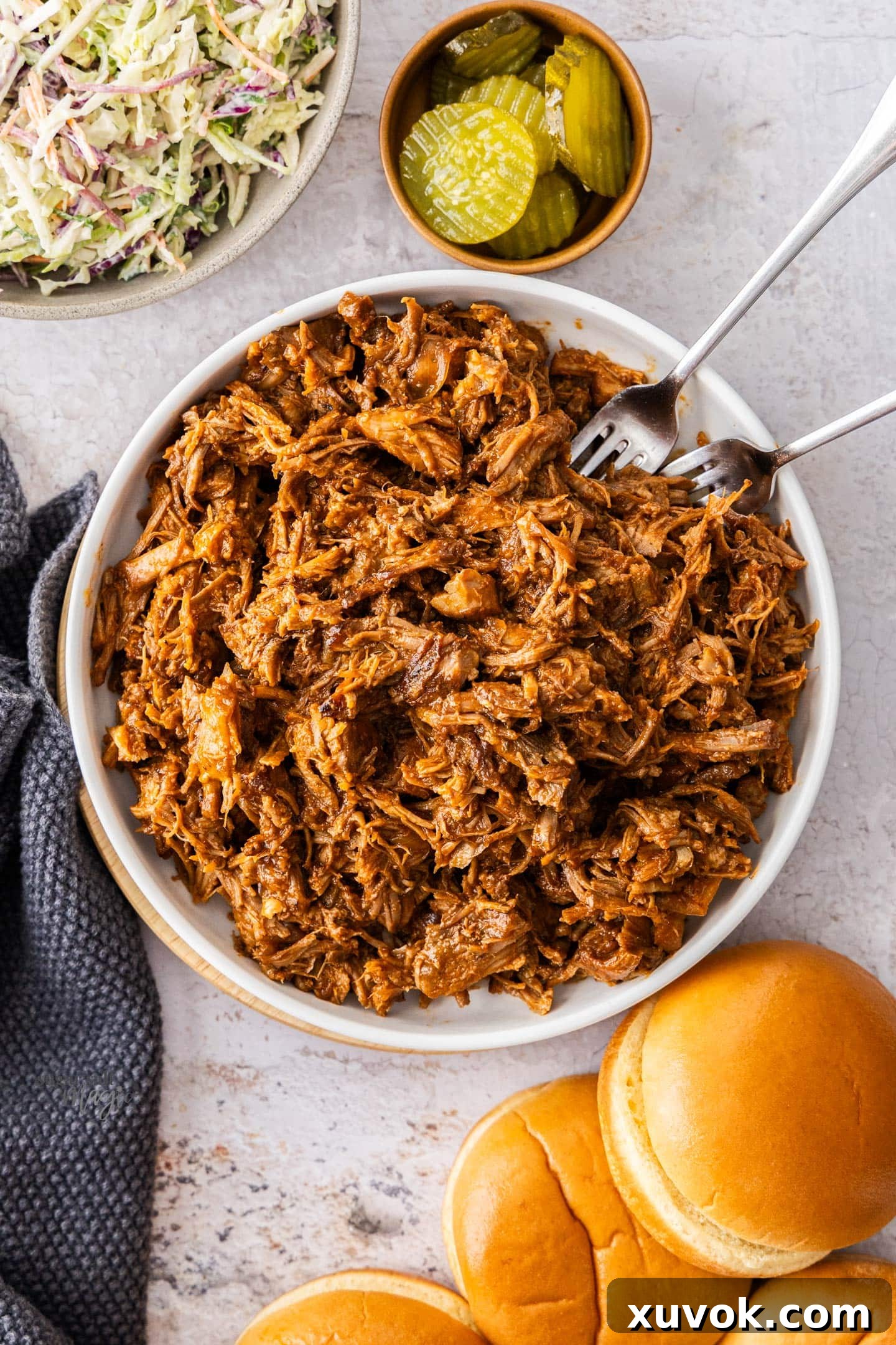 Top down view of a batch of bbq pulled pork in a white bowl.