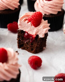 A batch of cupcakes with one cut open to show the raspberry puree middle.