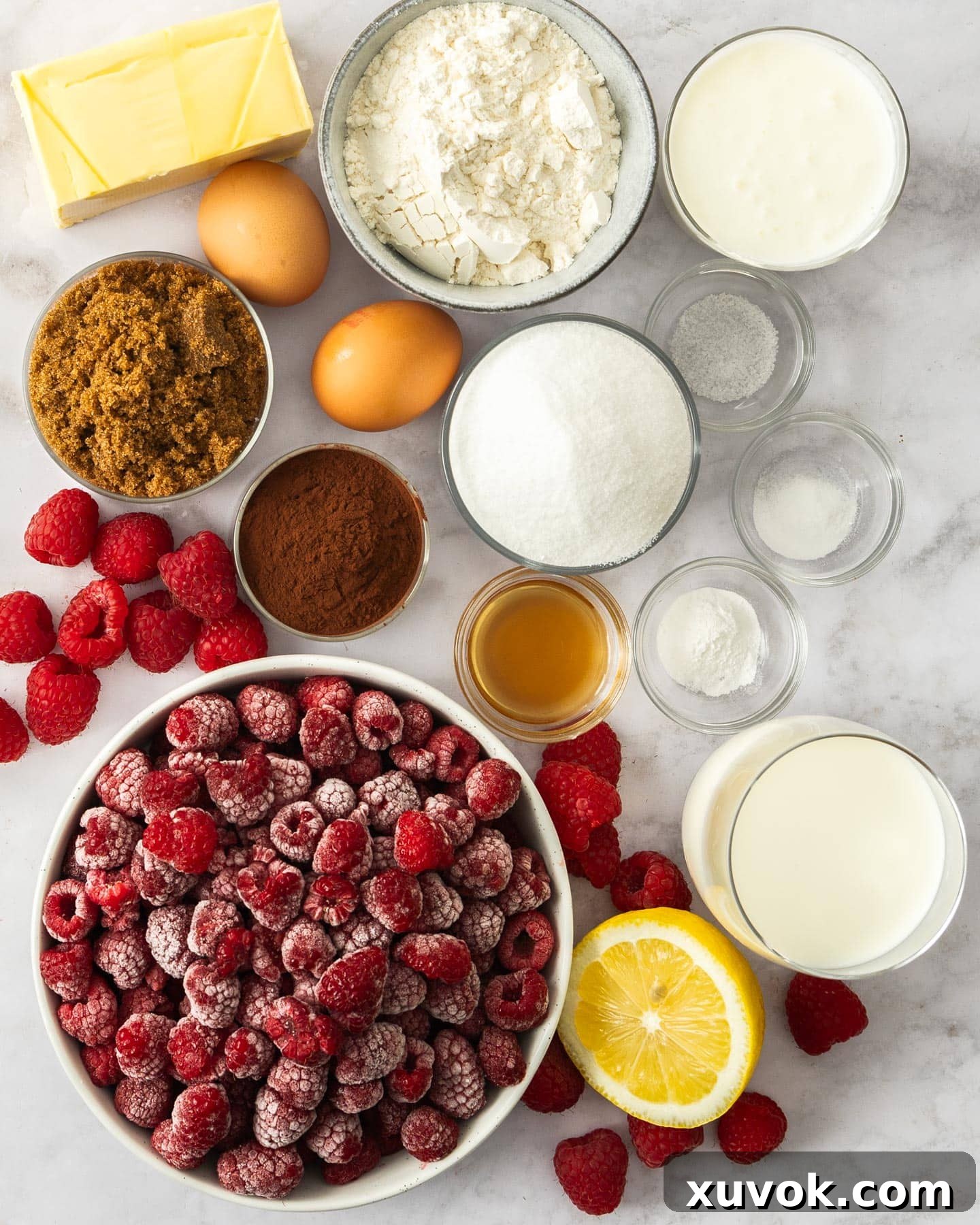 Ingredients for chocolate raspberry cupcakes arranged on a marble surface.