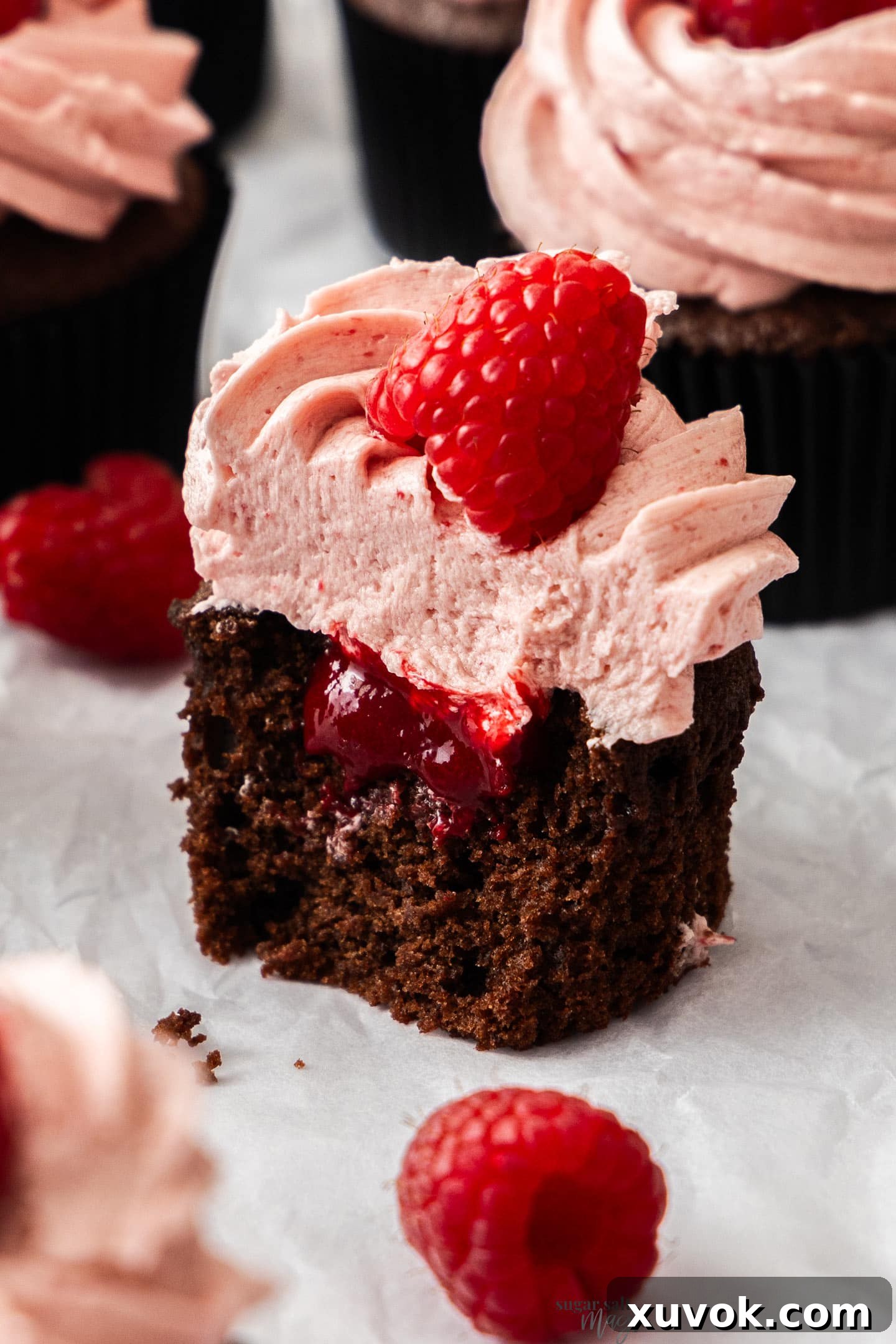Closeup of a chocolate raspberry cupcake cut open to show the raspberry filling.