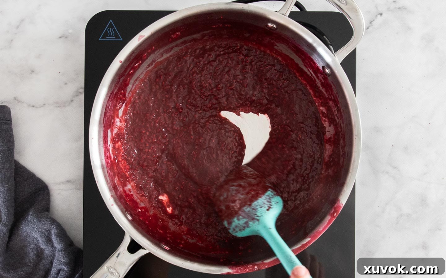 Raspberry puree simmering in a pan on the stove.