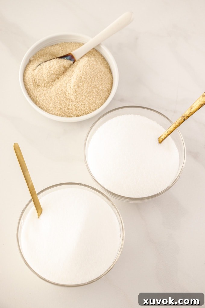 Three bowls showcasing different types of granulated sugar: Golden Caster, Granulated, and Caster Sugar, arranged with spoons.