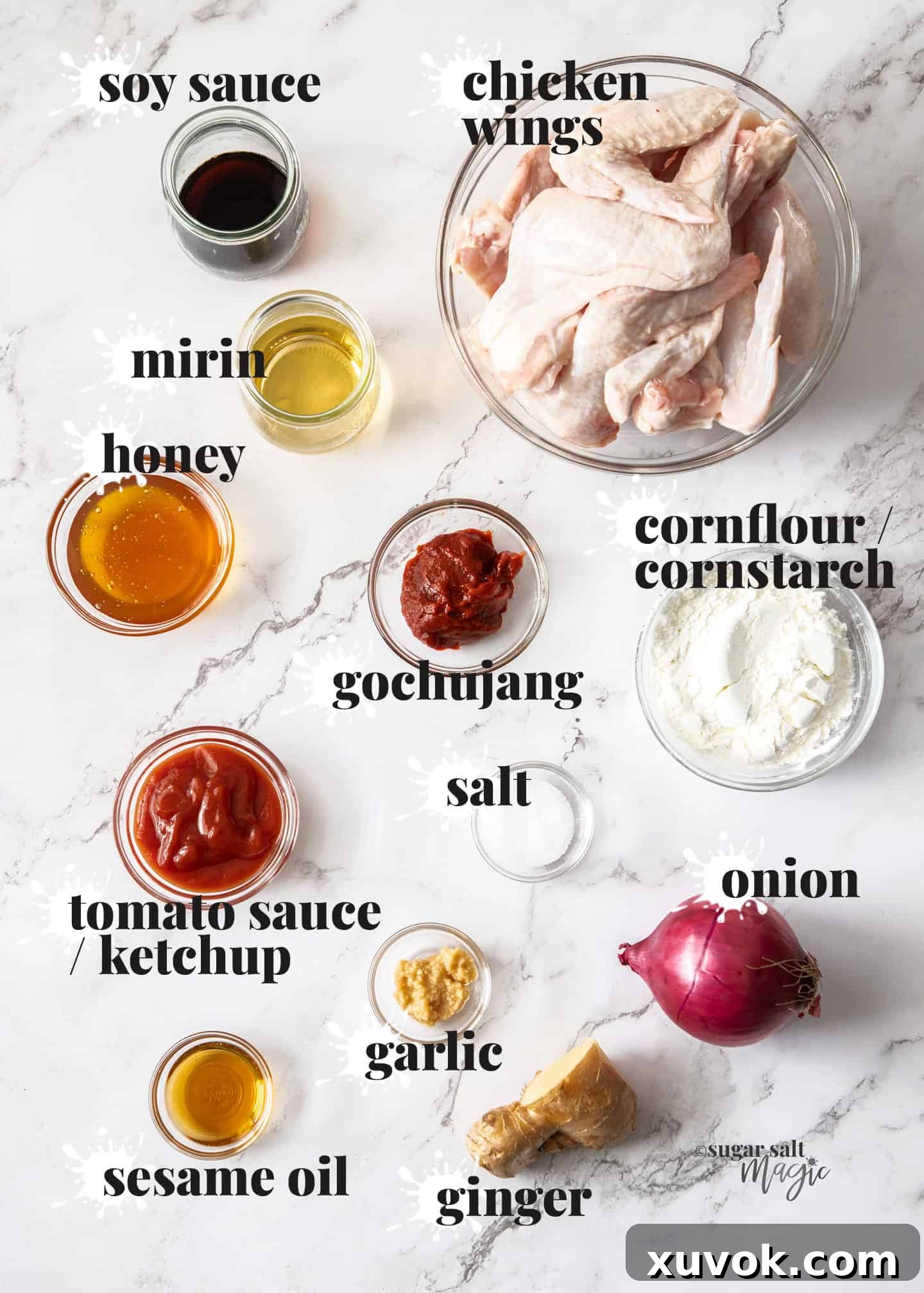 Ingredients for Korean fried chicken wings, including sauces, spices, and chicken, arranged on a marble worktop.