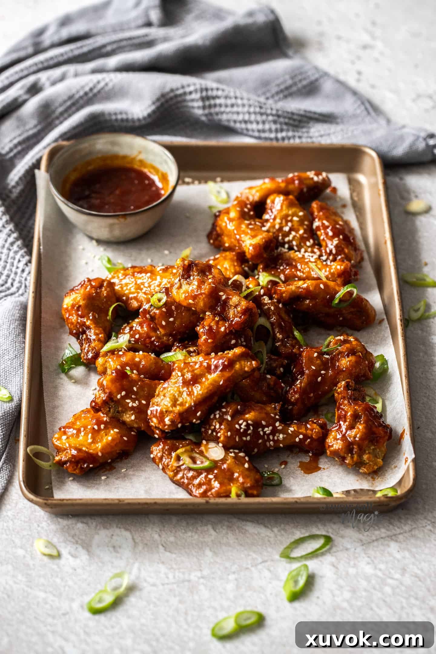A plate of fried sticky chicken wings, garnished with sesame seeds and spring onions, ready to be served.