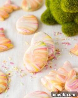 Iced sugar cookies stacked against each other surrounded by sprinkles