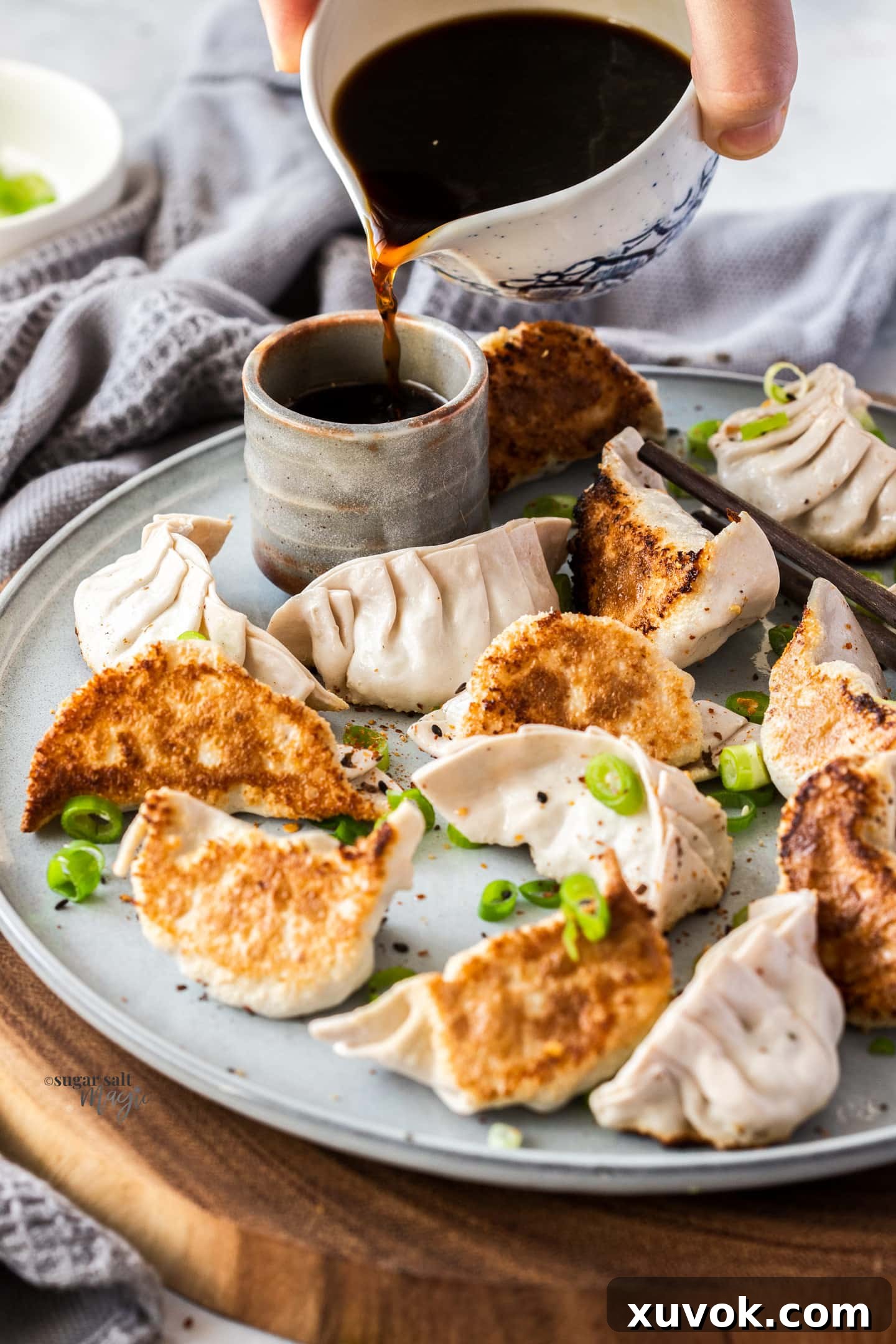 Sauce being poured into a small cup with gyoza on a plate, highlighting the delicious dipping experience.