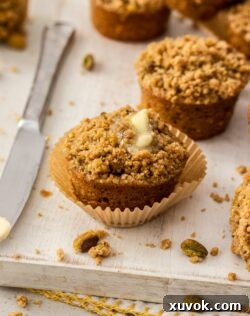 A close-up of a muffin topped with butter, with a knife next to it.