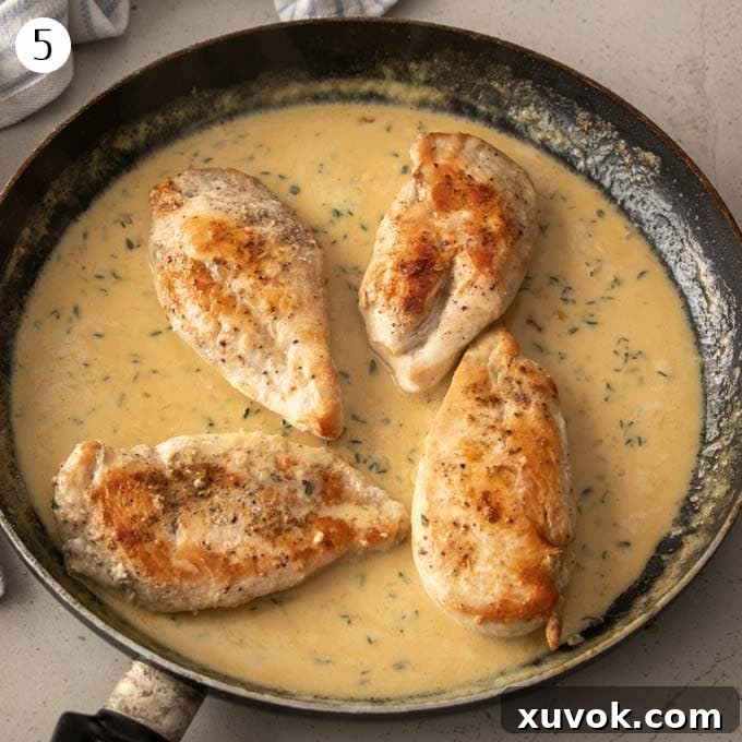 4 golden-brown chicken breasts nestled in a rich, creamy lemon thyme sauce in a skillet.
