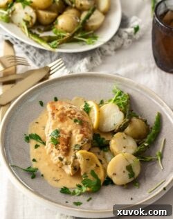 A grey plate with a chicken breast, potatoes and a cream sauce