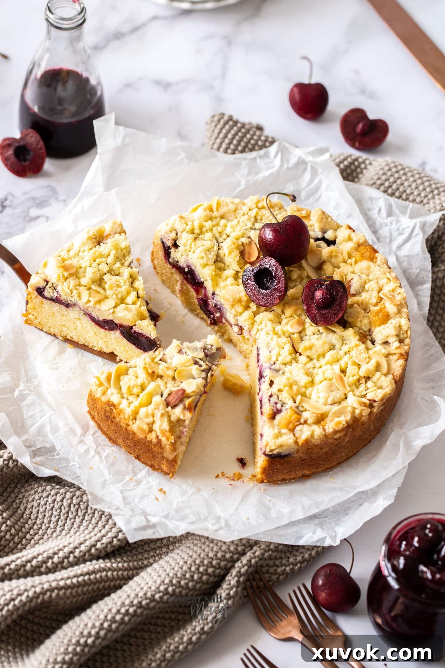A beautifully baked almond cherry crumb cake with two slices already removed, showcasing its delicious layers.