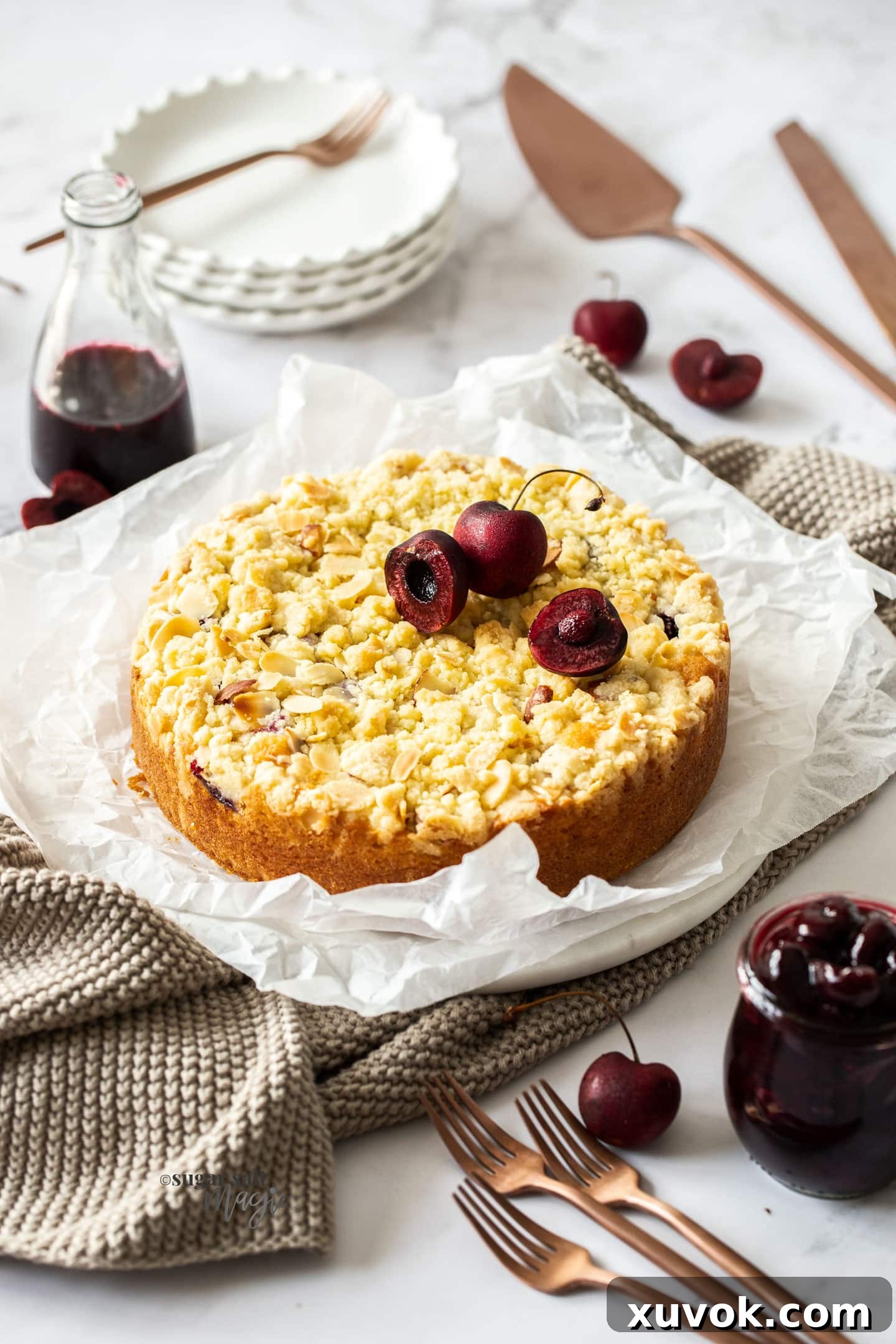 A delectable almond cherry crumb cake, rustic and inviting, resting on crumpled parchment paper with fresh cherries scattered around.