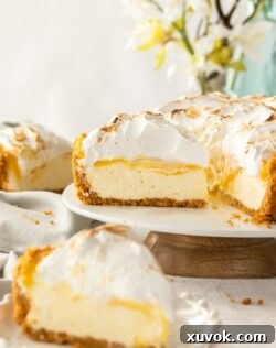 A cheesecake on a white cake plate with a blurred slice in the foreground
