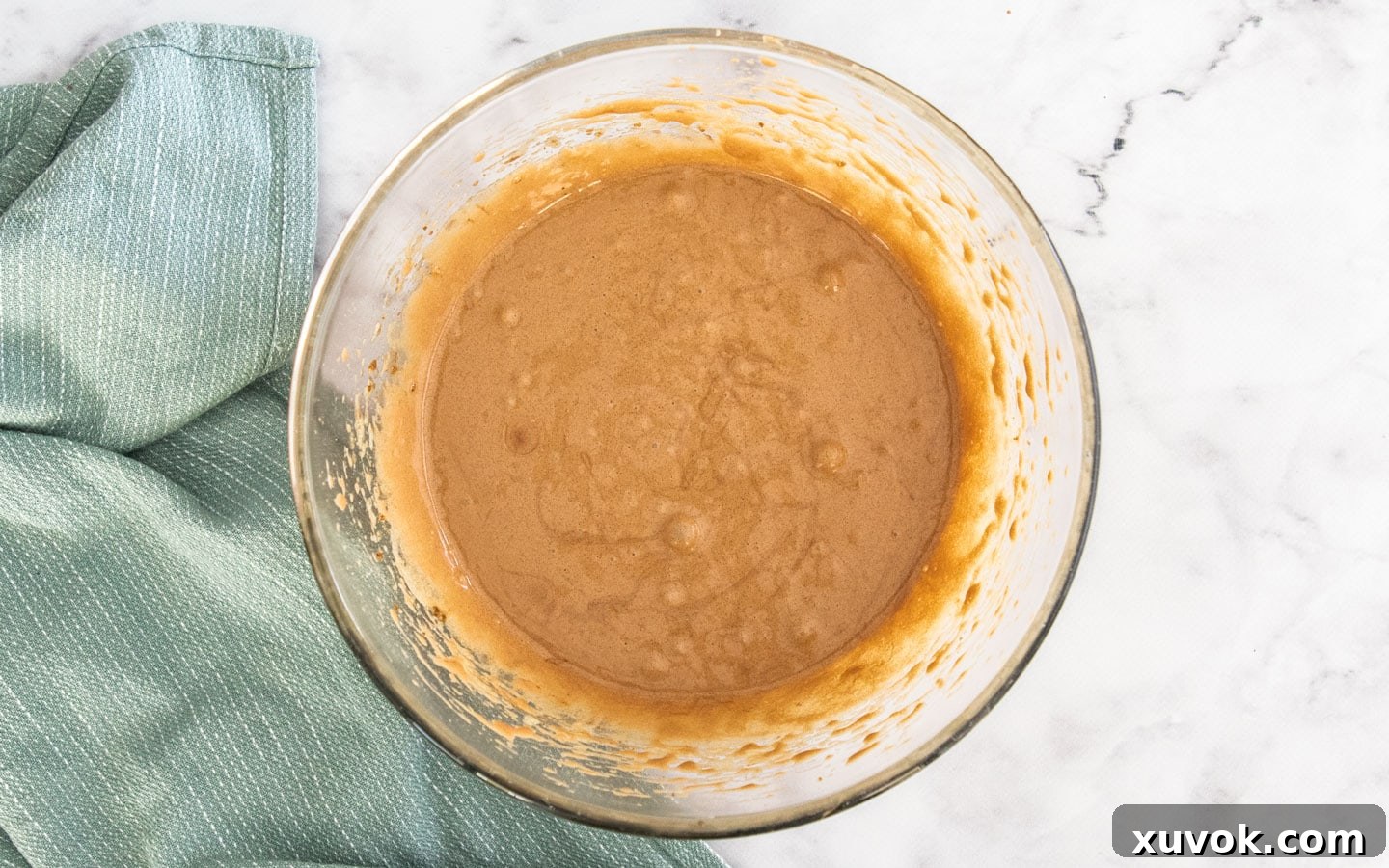 The wet ingredients for the brownie filling – eggs, sugars, melted chocolate, butter, and vanilla – mixed together in a bowl, creating a smooth base.