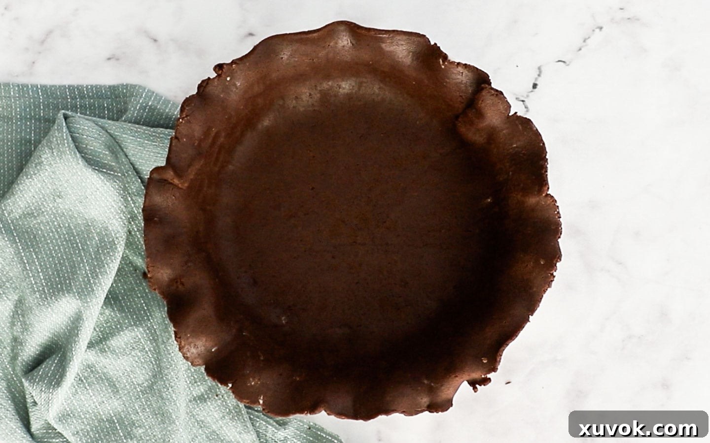 Gently placing the chocolate pie dough into a pie dish, preparing it for shaping.