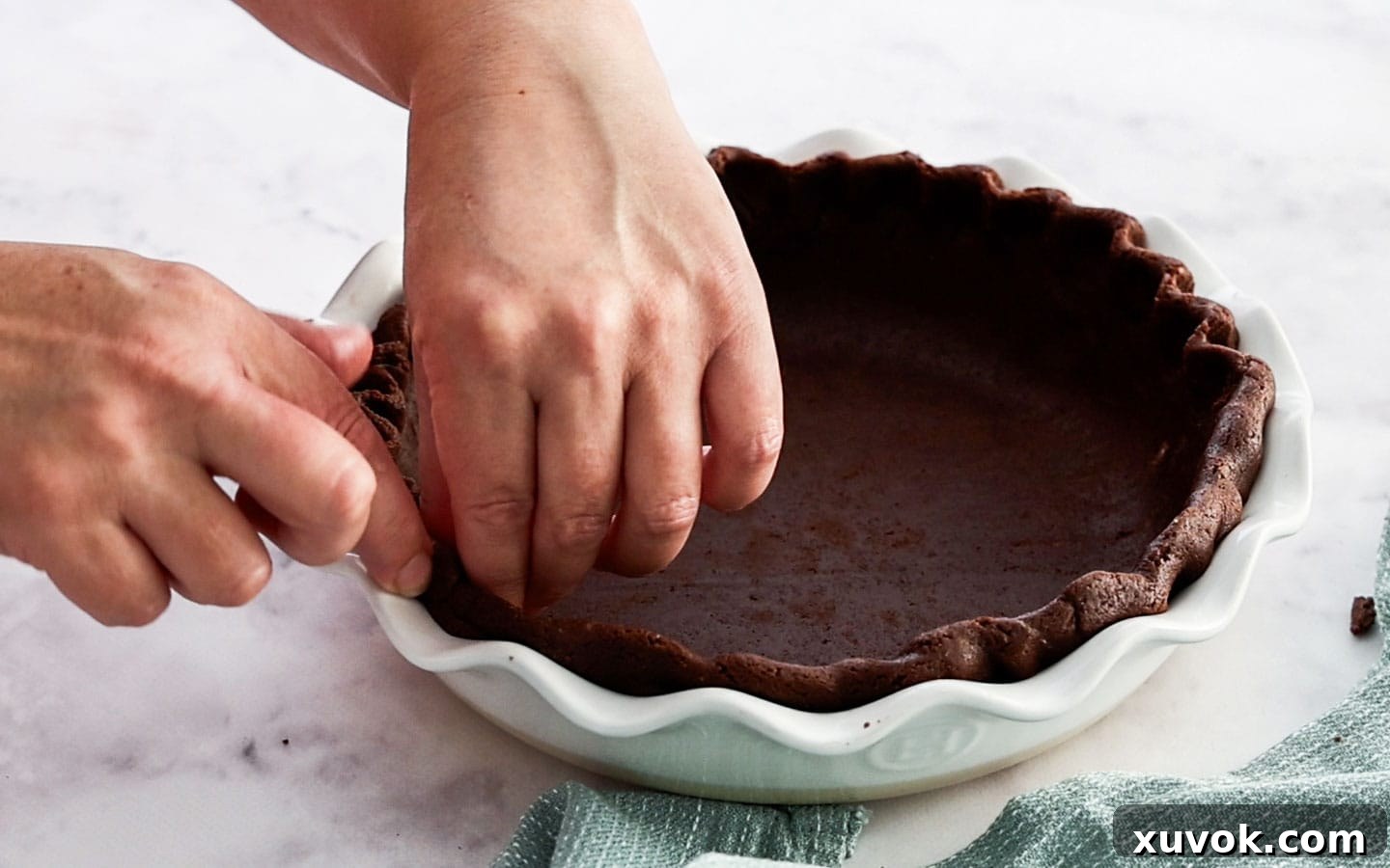 Artfully scalloping the edge of the chocolate pie dough in the pie dish, demonstrating the final shaping.