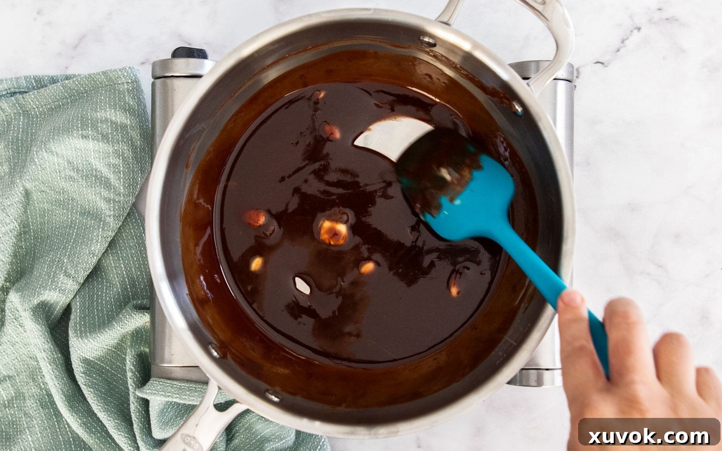 Butter and dark chocolate melting together in a saucepan over low heat, forming a rich, smooth mixture.