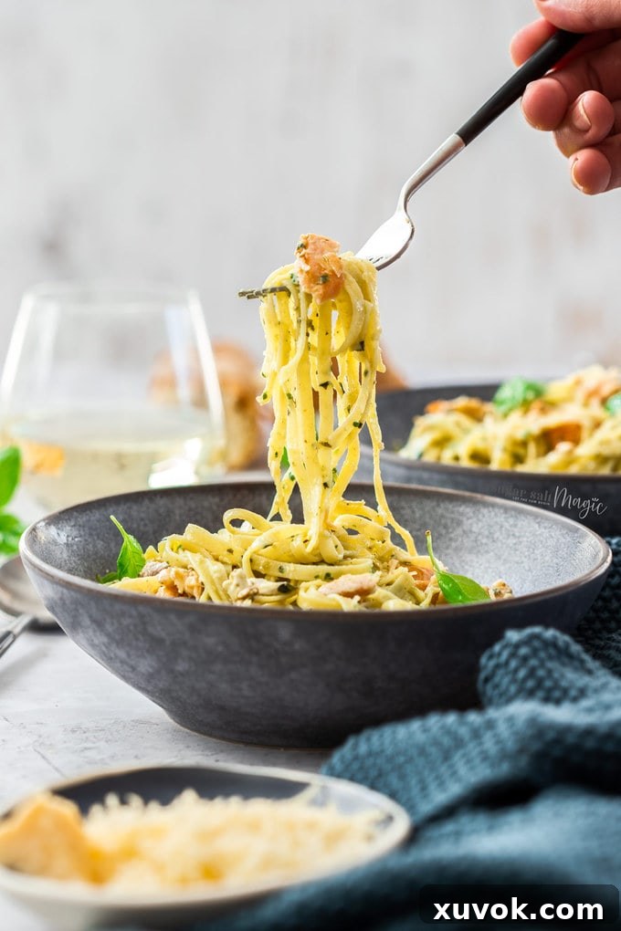 A Fork holding pasta over a grey bowl filled with pasta.
