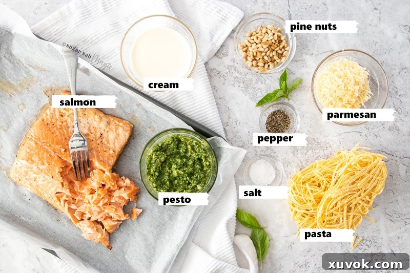 Ingredients for salmon pesto pasta laid out on a grey background.