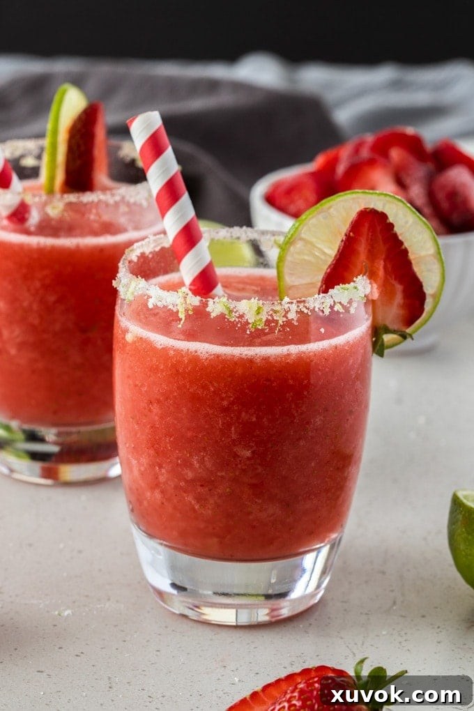 A frozen strawberry daiquiri in a glass with a red paper straw
