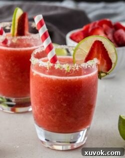 A frozen strawberry daiquiri in a glass with a red straw