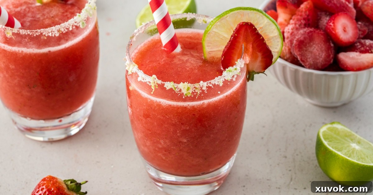 Closeup shot of a frozen strawberry daiquiri cocktail garnished with a slice of strawberry and lime
