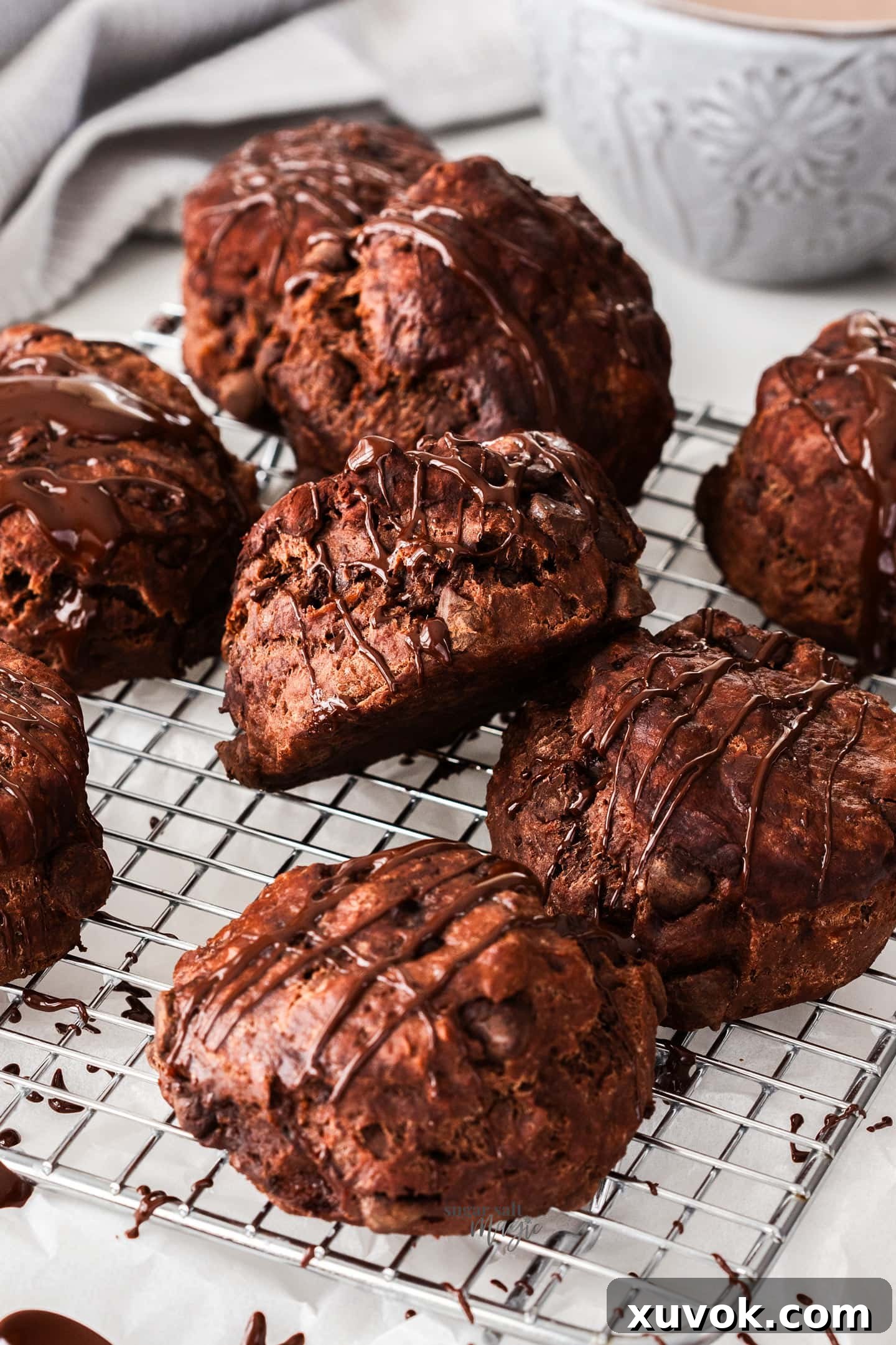 A batch of freshly baked chocolate scones cooling on a wire rack, ready to be drizzled with melted chocolate.