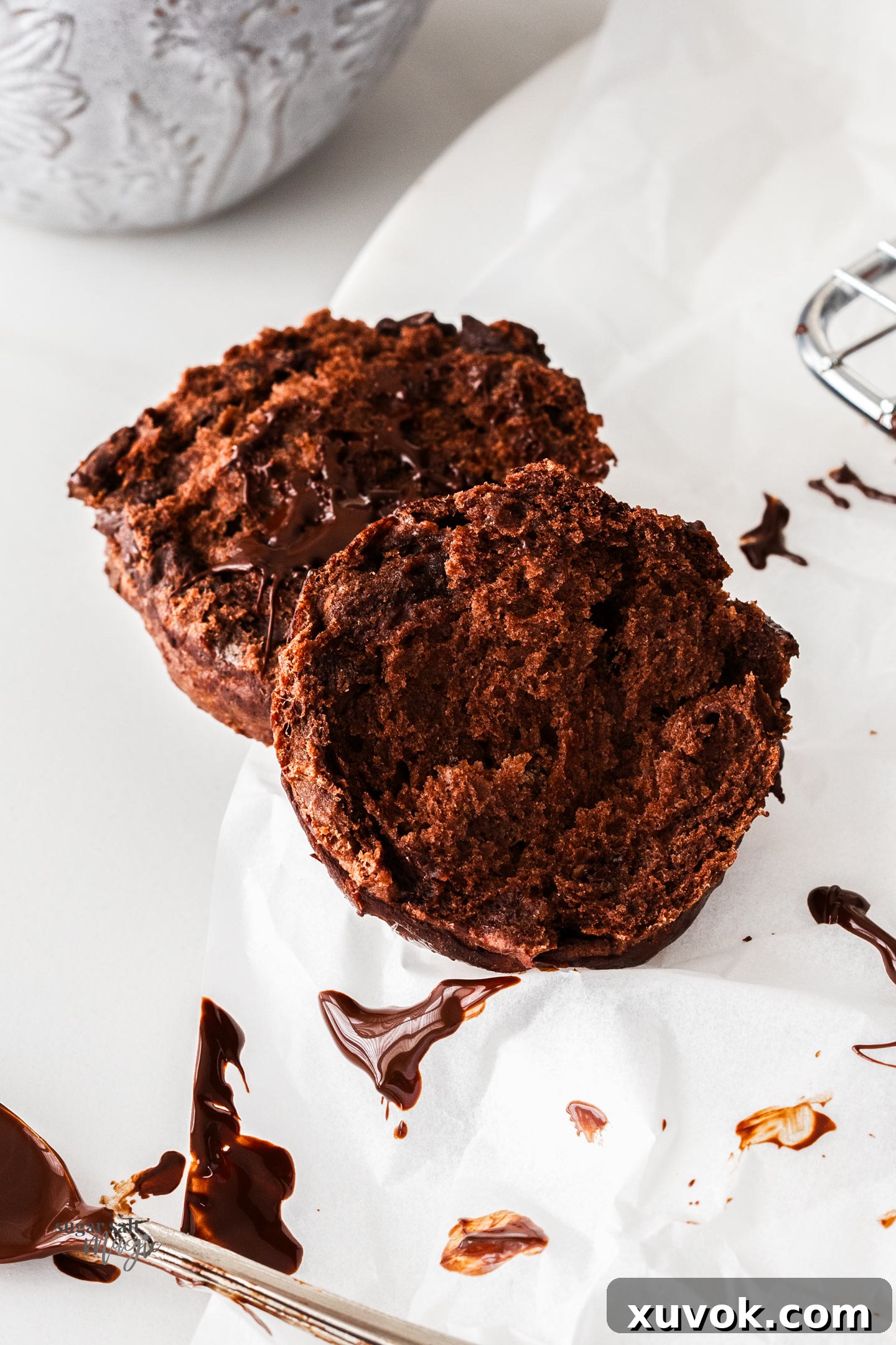 A chocolate scone torn in half, revealing its tender, fluffy inside with melted chocolate chips.