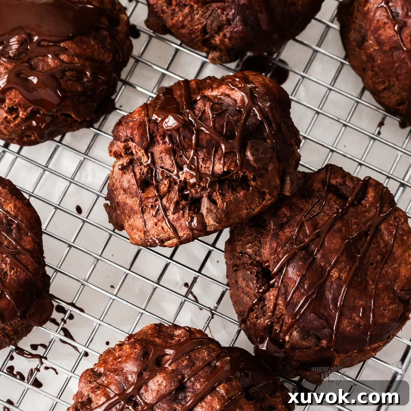 Close-up shot of a freshly baked chocolate scone on a wire rack, beautifully drizzled with melted chocolate.