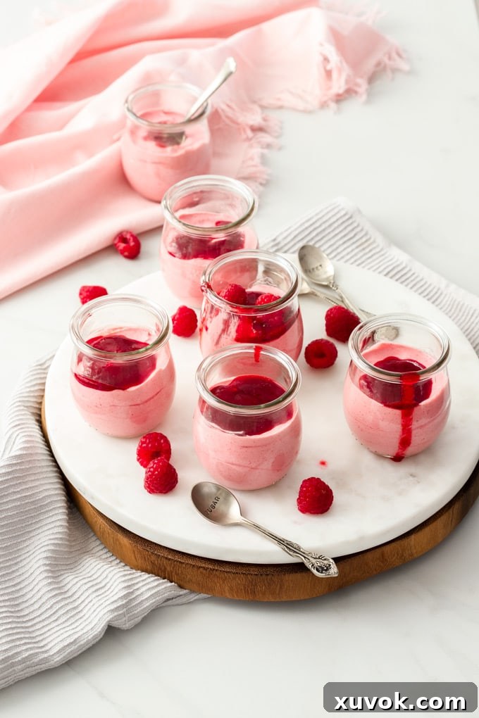 5 small glass pots of pink mousse sitting on a white marble platter