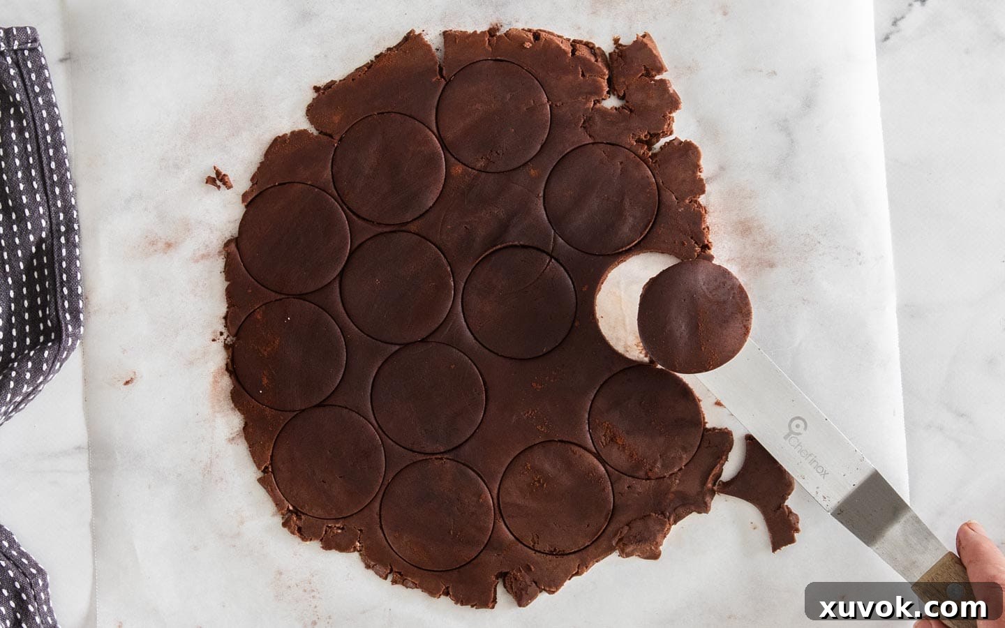 A close-up shot of round cookie cutters pressing into the rolled-out chocolate shortbread dough, creating uniform shapes.